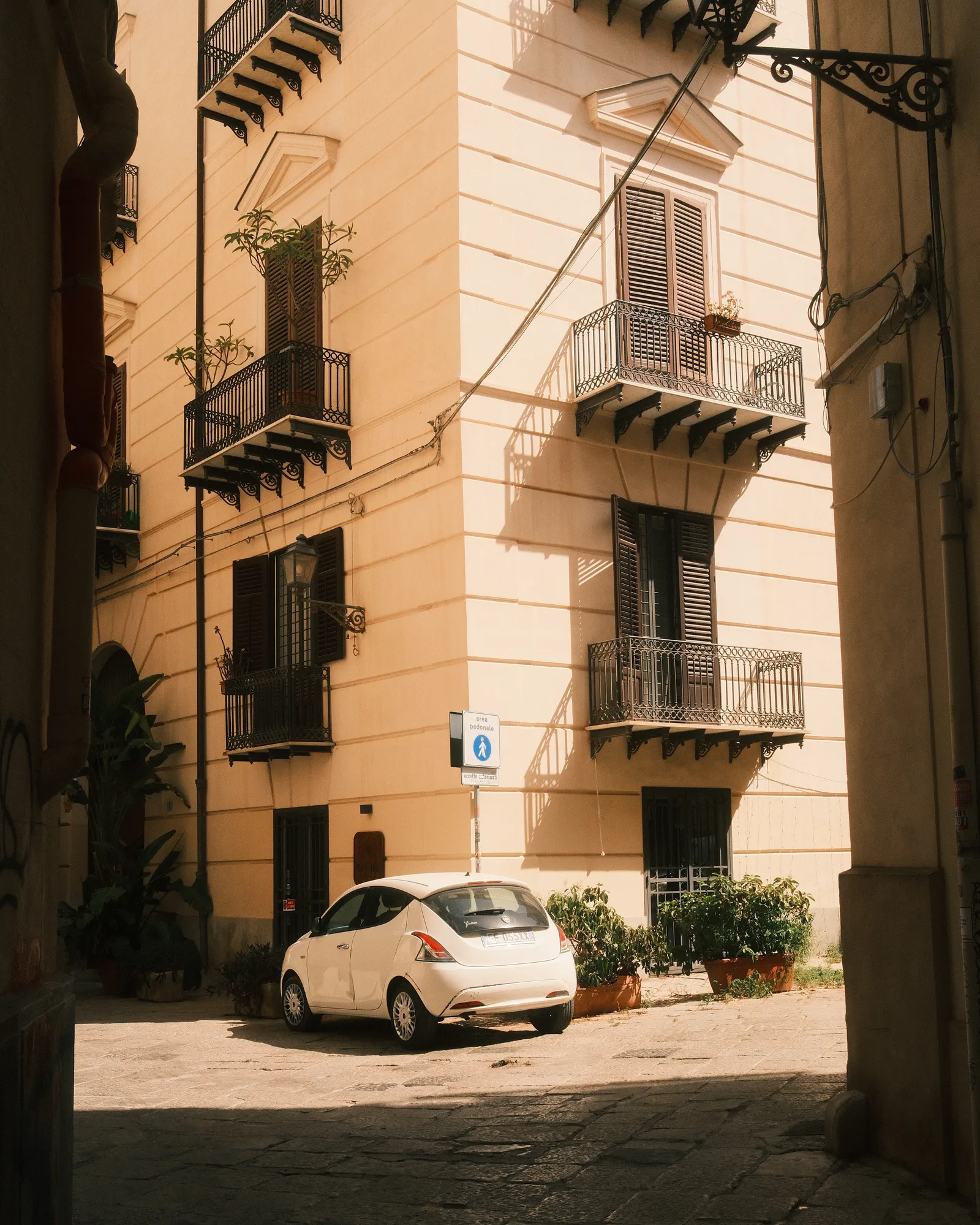 A white car parked at a corner in Palermo, Sicily