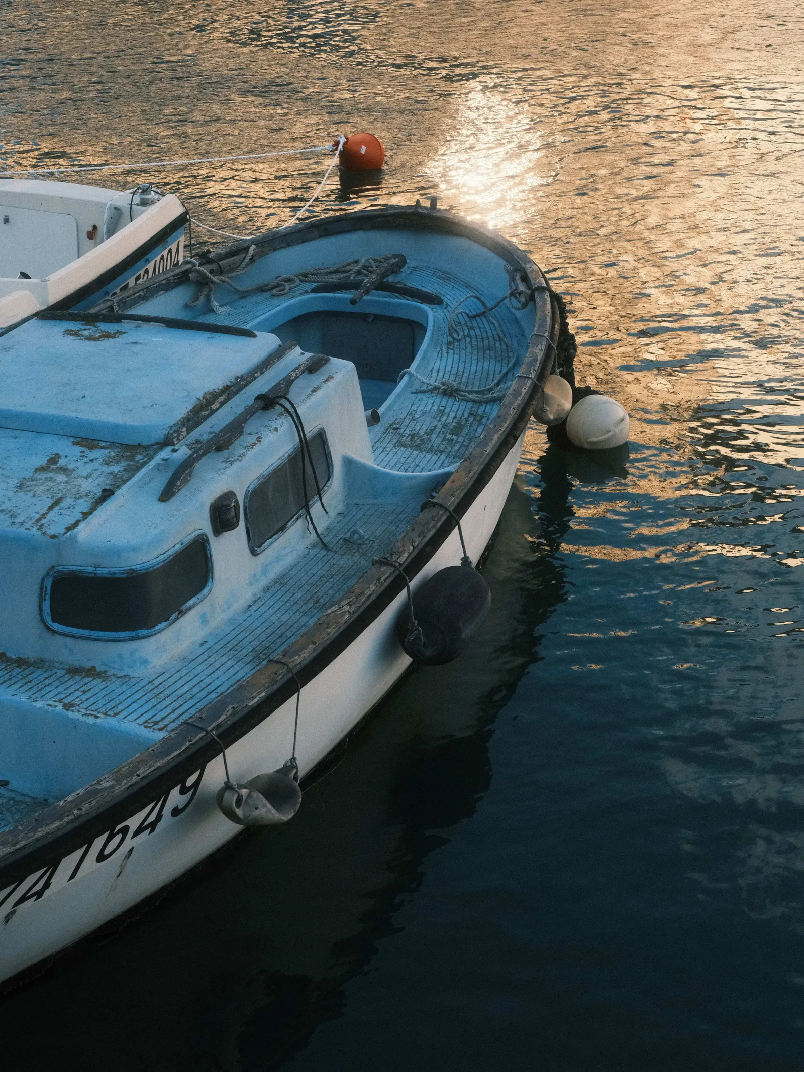 Blue and white fishing boat moored in Sete harbour, low sun reflecting off the water, Last Summer Roll recipe