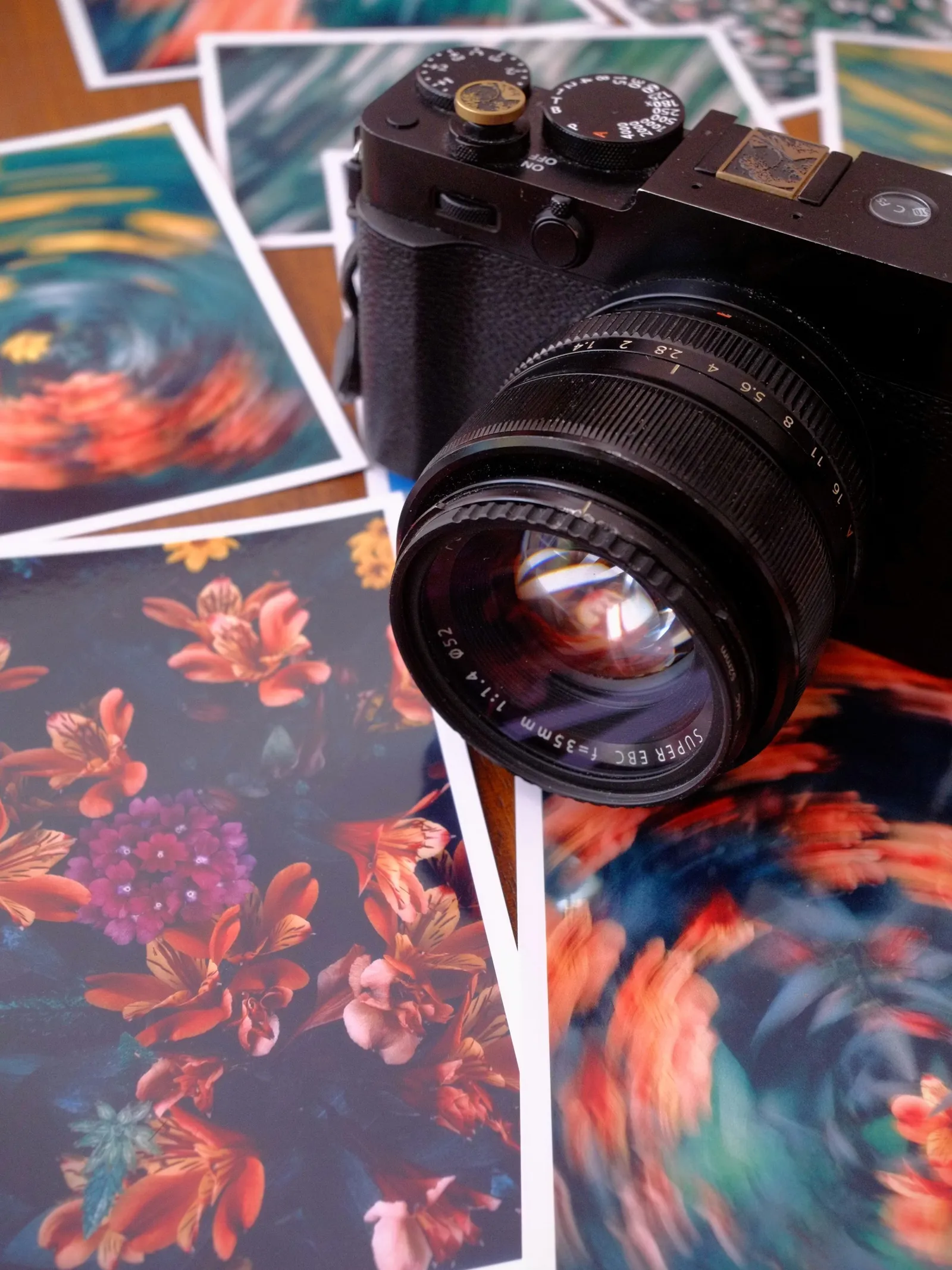 Fujifilm X-E5 with the XF 35mm f/1.4 resting on a scattered stack of prints