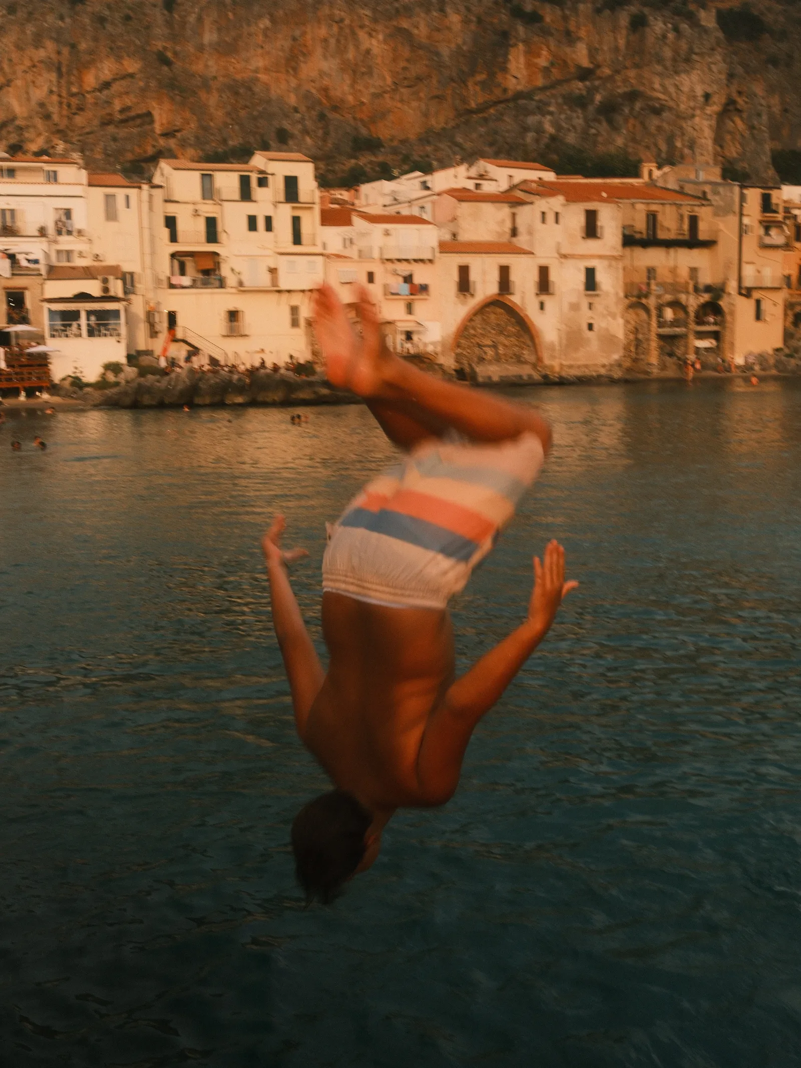 A boy jumping in the water in Cefalu, Sicily