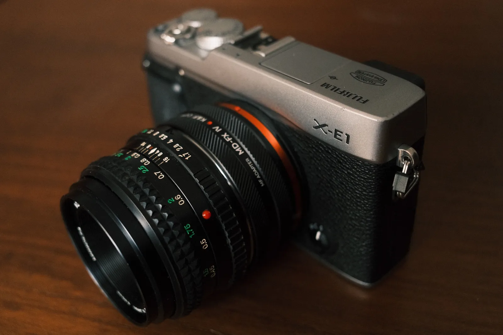 Silver Fujifilm X-E1 with a vintage manual lens on an MD to FX adapter, an example of a cheap way into the system