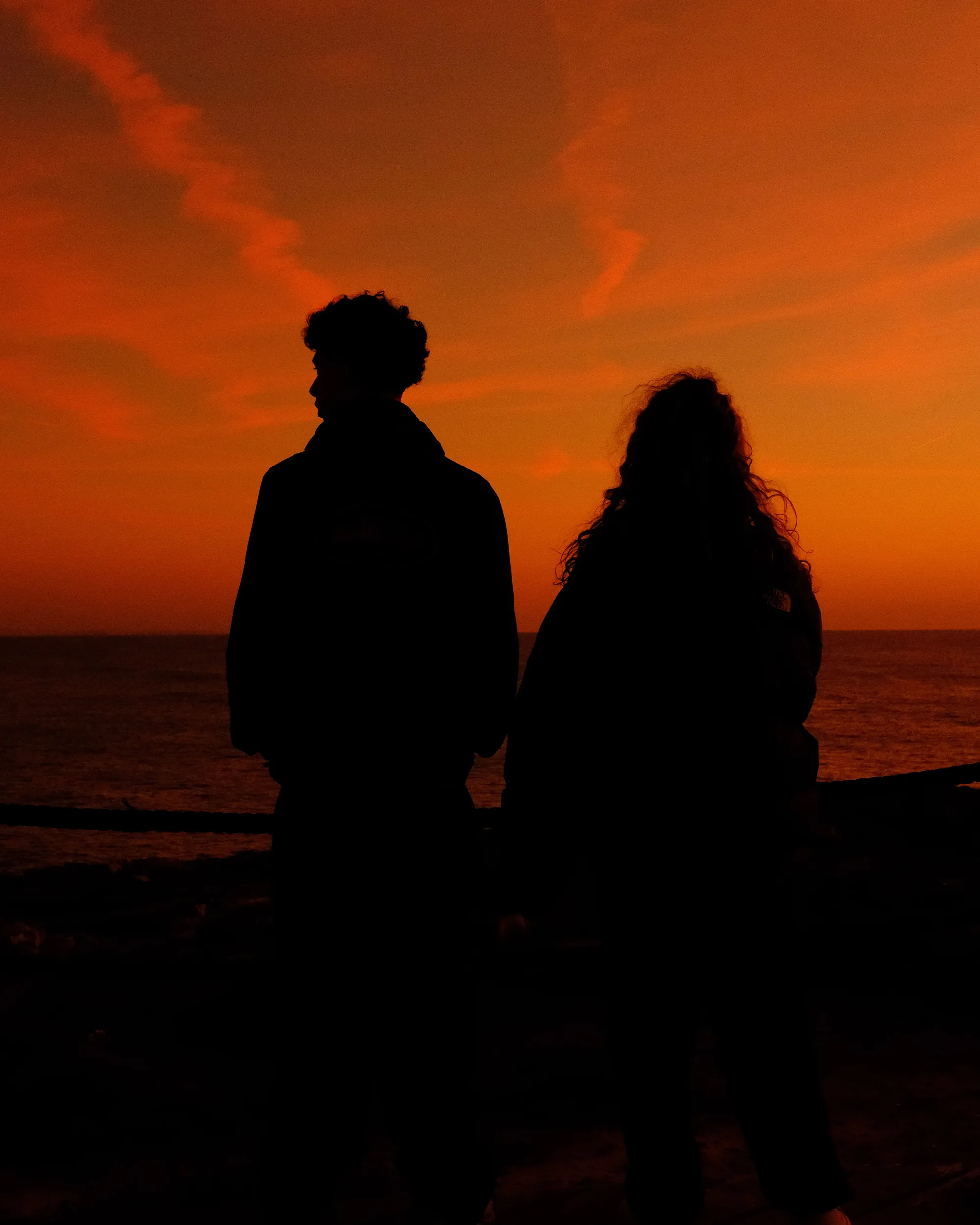 Two silhouettes facing the sea under a burning orange sky - Fujifilm Velvia settings